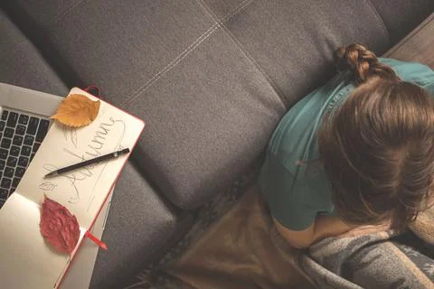 Cozy home template with notepad on sofa and laptop. Girl at home relaxing in  Stock Photos