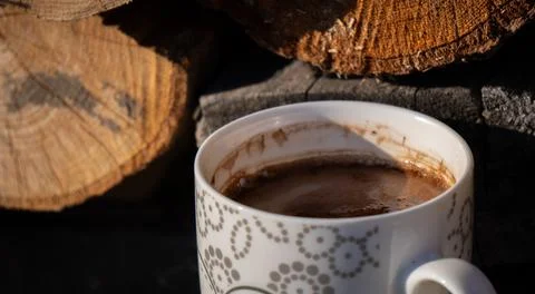 Cozy Hot Chocolate Mug with Pattern on Woodpile Illuminated by Warm Sunligh.. Stock Photos