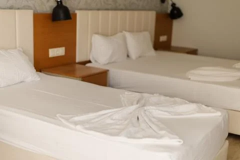 This cozy hotel room features two neatly made beds with soft white bedding. T Stock Photos