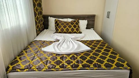 Cozy hotel room with patterned bedding and sunlight Stock Photos