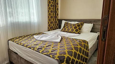 Cozy hotel room with patterned bedding and sunlight Stock Photos