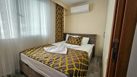 Cozy hotel room with patterned bedding and sunlight Stock Photos