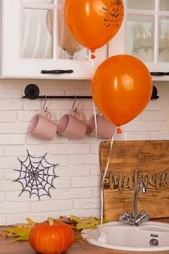 Cozy kitchen decorated for Halloween. Two orange balloons float above sink. A Stock Photos