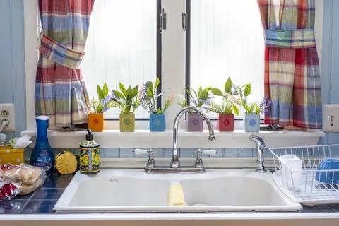 Cozy Kitchen Interior with Double White Sink and Vibrant Window Decor Fotos de archivo