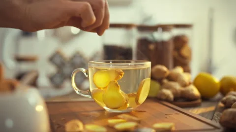 In a cozy kitchen a mans hand carefully adds a slice of fresh ginger to stea Stock Footage 331461427