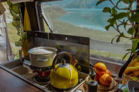 A cozy kitchen scene inside a camper van with a yellow kettle, fruits, and a Stock Photos