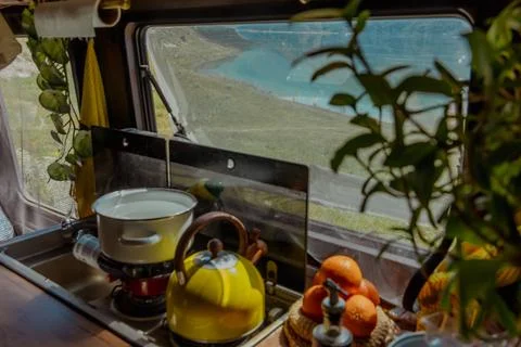A cozy kitchen scene inside a camper van with a yellow kettle, fruits, and a Stock Photos