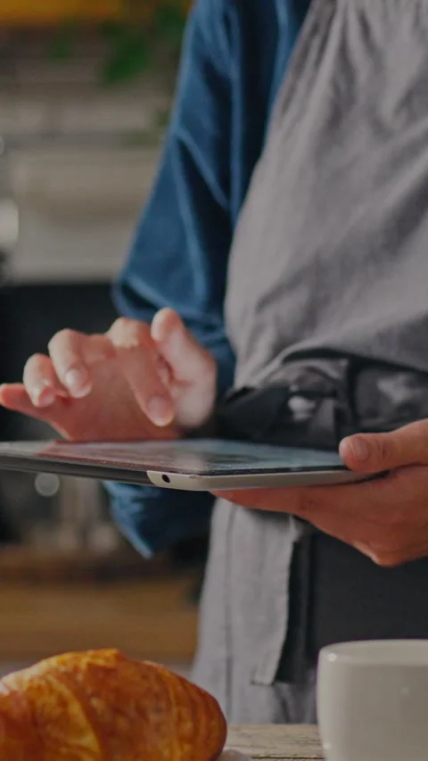 In a cozy kitchen a worker uses a touch tablet production and sale of baked Stock Footage 331599880