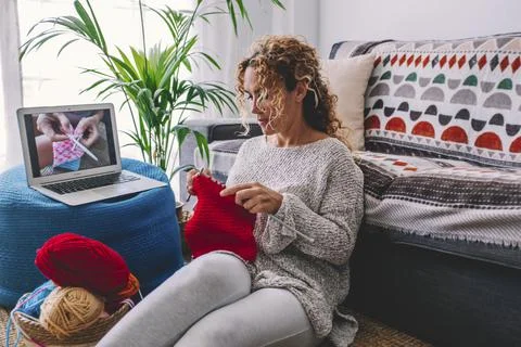 Cozy knitting woman follow tutorial in knitted winter warm sweater and in paj 库存照片