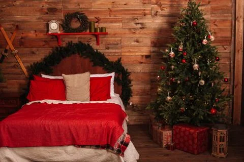 A cozy large double bed next to the Christmas tree on a holiday evening. New  Foto stock