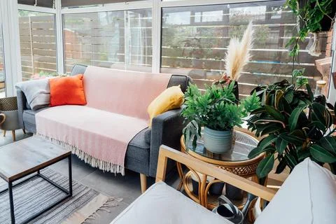 Cozy, light conservatory interior design with gray sofa decorated with bright Stock Photos
