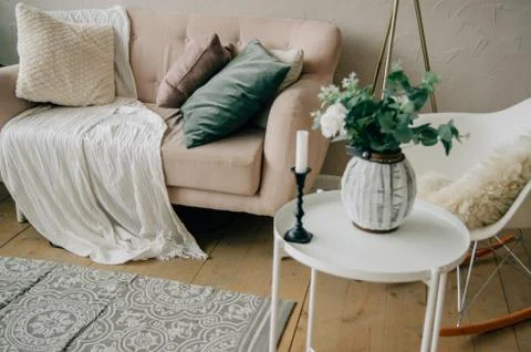 Cozy light interior. Soft beige sofa, white chair, round coffee table, floor  Stock Photos
