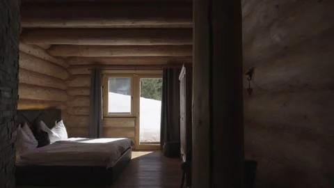 Cozy log cabin bedroom with a large bed and sunlight streaming through the Vidéo 335756847