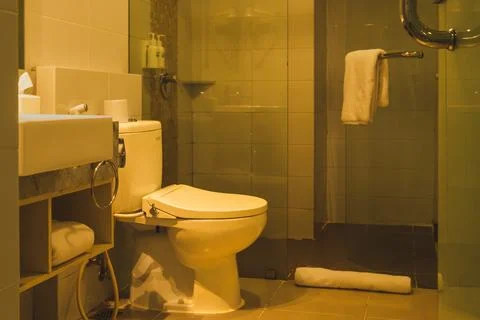 Cozy modern bathroom interior with ceramic toilet bowl sink and hanging towel Stock Photos