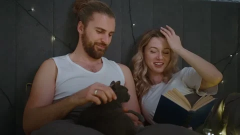 Cozy night in with a book and a cat by soft fairy lights Stock Footage 307106941