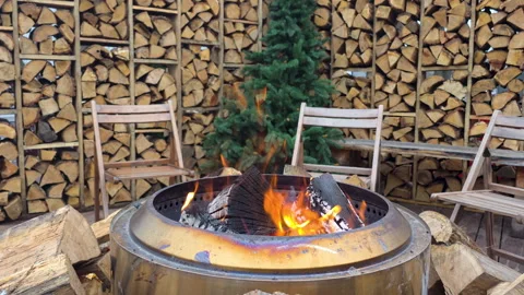 Cozy Outdoor Fire Pit Area With Seating and Neatly Arranged Wood Storage Stock Footage 324557536