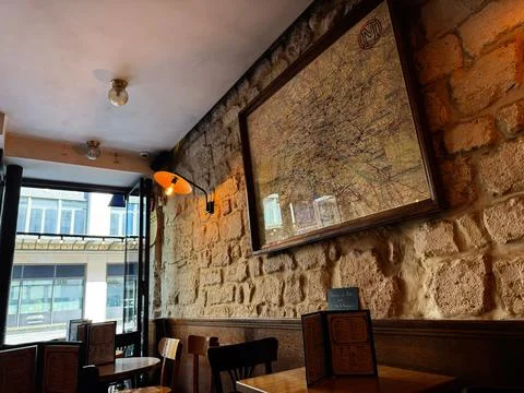 Cozy Paris cafe interior with framed vintage map on stone wall, wooden tabl.. Stock Photos