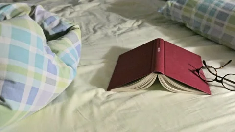 Cozy Red book on Bedside Bed with Glasses and Pillow, Morning Reading Scene Stock Footage 320288296