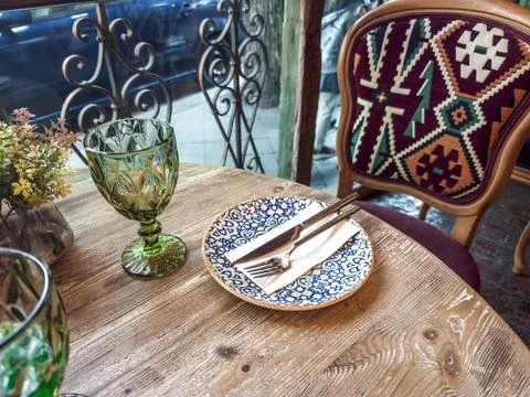 Cozy restaurant table setting with patterned plate, cutlery on a napkin, gree Stock Photos