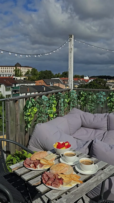 Cozy rooftop terrace breakfast table with city background. Video stock 344880093