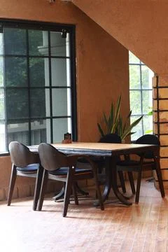 Cozy rustic indoor café corner featuring wooden tables, vintage chairs Stock Photos