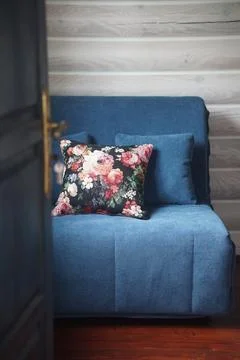 A cozy rustic room interior with a soft blue sofa and a decorative floral p.. Stock Photos