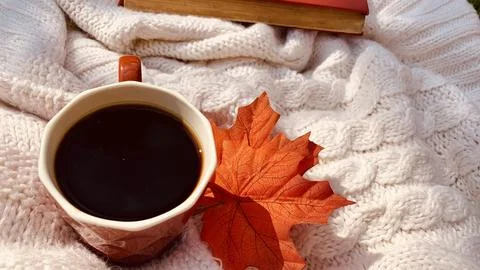 A cozy setting features a cup of black coffee resting on a soft knitted blanket Stock Photos