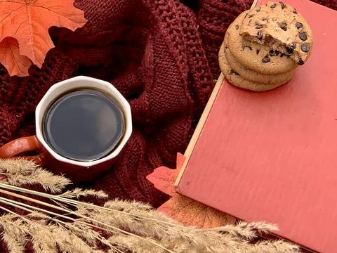 A cozy setting features a warm cup of coffee, chocolate chip cookies, a red Foto stock