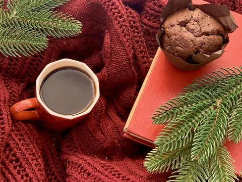 A cozy setup featuring a red mug filled with coffee, a chocolate muffin wrapped Stock Photos