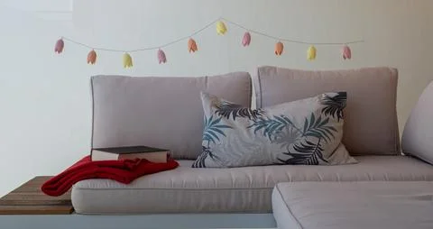 A cozy sofa with patterned cushions, a red blanket, and string lights. Stock Photos