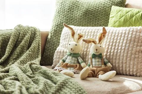 Cozy Sofa with Plush Easter Bunny Dolls and Textured Pillows in Sunlight Stock Photos