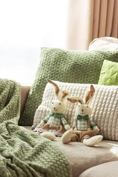 Cozy Sofa with Plush Easter Bunny Dolls and Textured Pillows in Sunlight Stock Photos