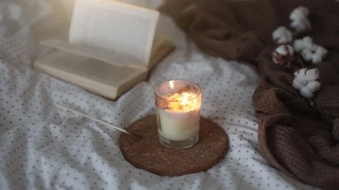 Cozy still life interior details with a book, burning candle and a cotton twig Stock Footage 172208853