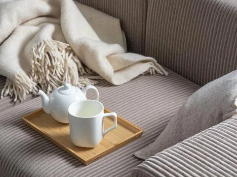 Cozy tea scene with white ceramic teapot and mug on a bamboo tray, resting .. Stock Photos