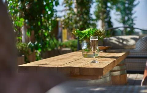 Cozy terrace with sofas for rest, Glass with champagne on a wooden table. Stock Photos