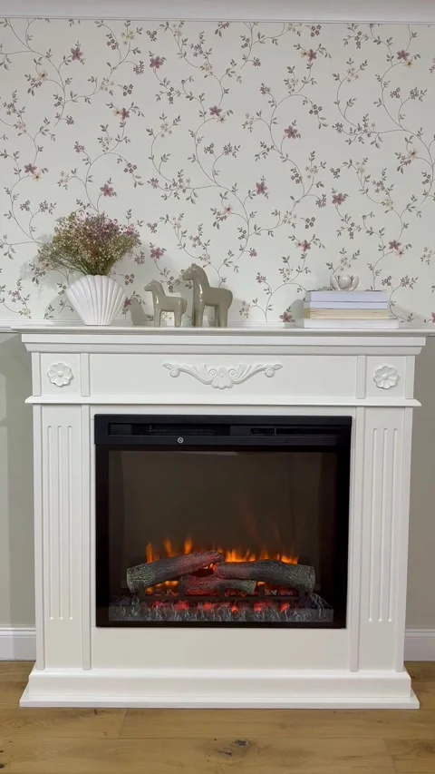 Cozy White Electric Fireplace with Glowing Logs and Floral Decor Stock Footage 332947148