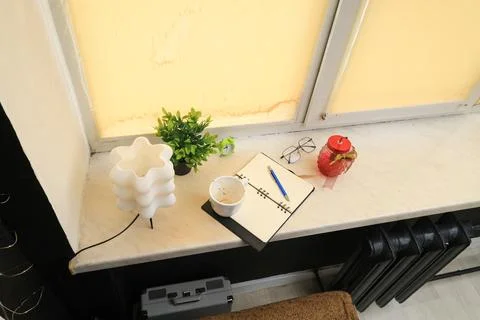 Cozy windowsill setup with a lamp, notebook, and decorative jar 스톡 사진