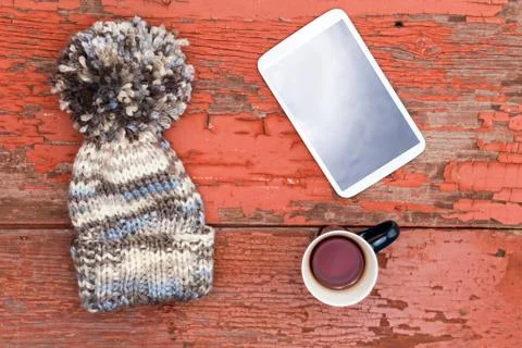 Cozy winter cap, tablet and tea on a grungy table Stock Photos