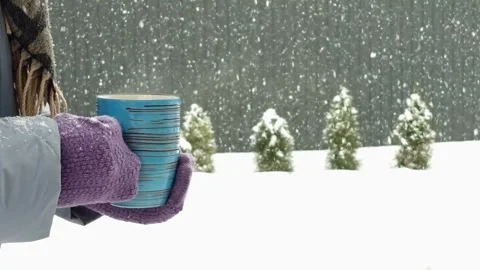 Cozy winter scene with a warm drink and falling snow outside Stock Footage 330761548
