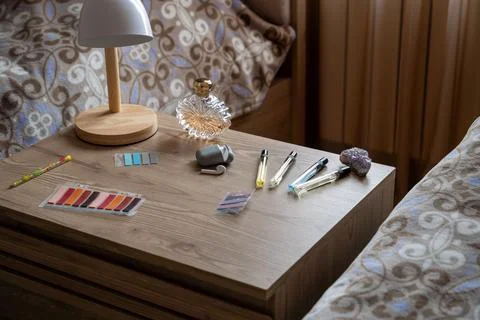Cozy wooden bedside table with a modern lamp, perfume bottles. Stock Photos