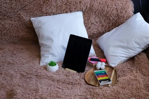 Cozy workspace setup with tablet, art supplies, and fluffy blanket Stock Photos