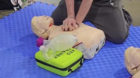 CPR Training and First Aid Instruction with Mannequin, AED Trainer Stock Footage 341558008