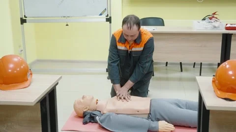 CPR training session with worker performing chest compressions on a mannequin Stock Footage 274490425
