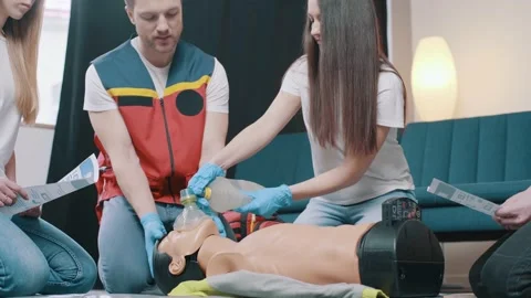 CPR training using and an AED and bag mask valve on an adult training manikin Stock Footage 234429836