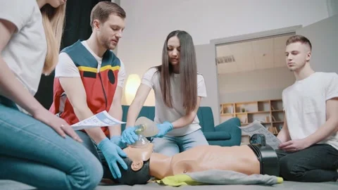 CPR training using and an AED and bag mask valve on an adult training manikin Stock Footage 234429877