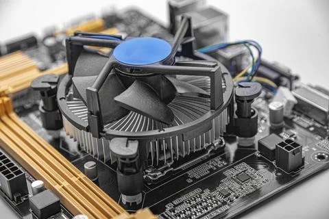 CPU cooler mounted on a black and orange computer motherboard. Stock Photos