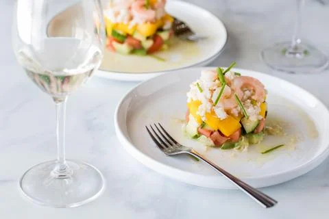 Crab and shrimp stack salads garnished with chives and served with white wine. Foto stock