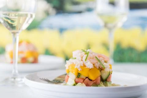 Crab and shrimp stack salads served with white wine against a blurry garden. Stock Photos