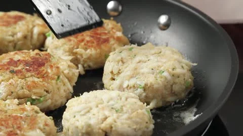 Crab cakes being fried in a pan Stock Footage 24652216