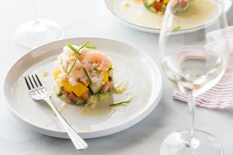 A crab stack salad served with white wine and light coming from behind. 스톡 사진